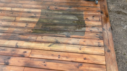 Rensning af træterrasse i gang med professionelt udstyr og fjernelse af alger