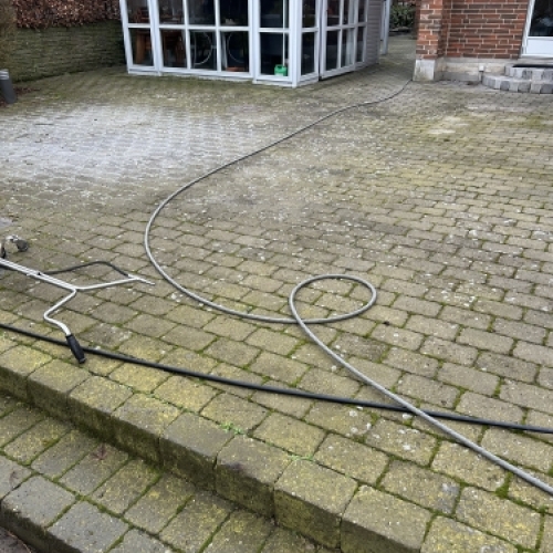 Fliserens i gang med højtryksrensning af terrassebelægning