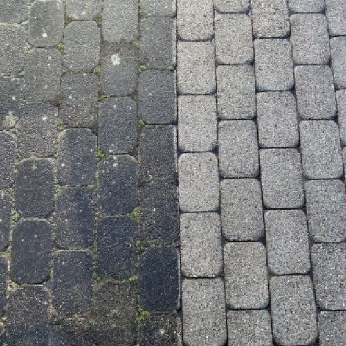 Før og efter fliserens på brostensbelægning med tydelig farveforskel