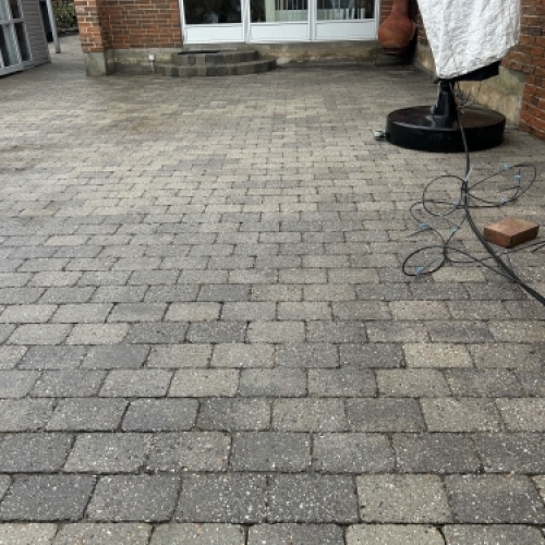 Før og efter fliserens med tydelig forskel på renset og urenset belægning