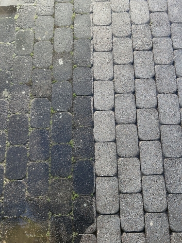 Før og efter fliserens på brostensbelægning med tydelig farveforskel